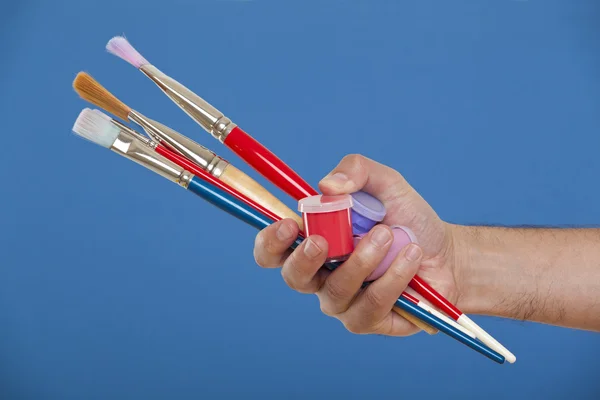 Hand holding several brushes and paint — Stock Photo, Image