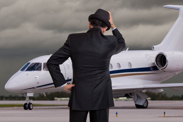 Business man holding his head in front of private airplane