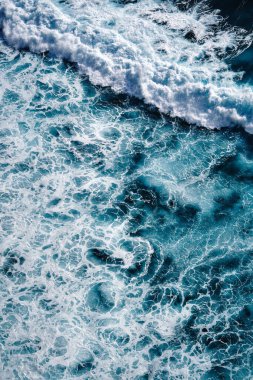 Okyanustaki su sıçrayan dalgaların hava görüntüsü. Mavi temiz dalgalı deniz suyu