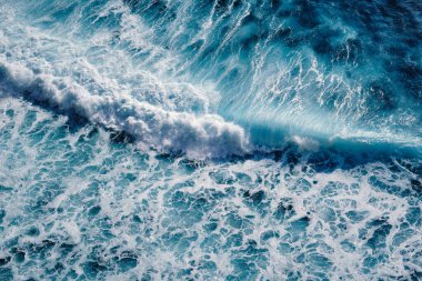 Okyanustaki su sıçrayan dalgaların hava görüntüsü. Mavi temiz dalgalı deniz suyu