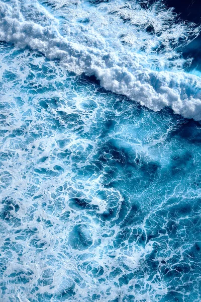 Okyanustaki su sıçrayan dalgaların hava görüntüsü. Mavi temiz dalgalı deniz suyu