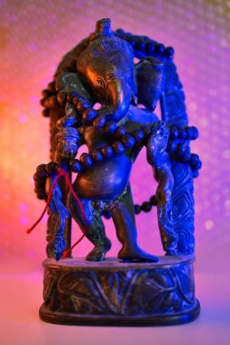 Hindu Tanrısı - Rudraksha tespihiyle renkli bir ışıkta Tanrı Ganesha. Tanrı Ganesha 'nın renkli fotoğrafı..