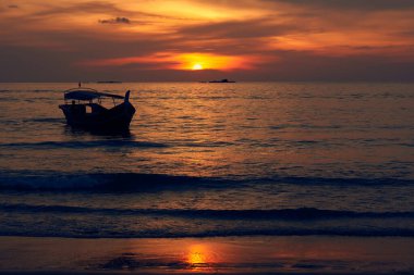 Altın günbatımına karşı teknenin silueti. Gün batımı Pantai Cenang plajı üzerinde, Langkawi, Malaisiya.