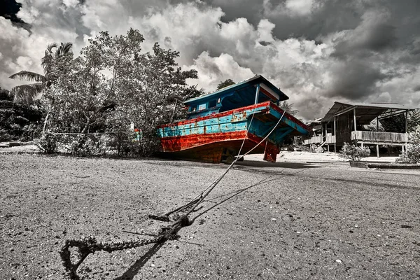 The sea tide with a old colorful asian fishing boats and dramatic sky on the background. Traditional asian fishing village, Langkawi island, Malaysia. Color in bw, color splash effect.