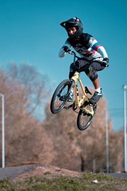 Moskova, Rusya - 18 Ekim 2019: Genç bir çocuk pompa pistinde BMX motoruyla atlıyor. BMX yarışı. Pompa pistinde bisiklet sürüyor. Sürücü bisiklet sporunda iş başında. Bisikletli havalı bir sporcu. Pompalama bisikleti.