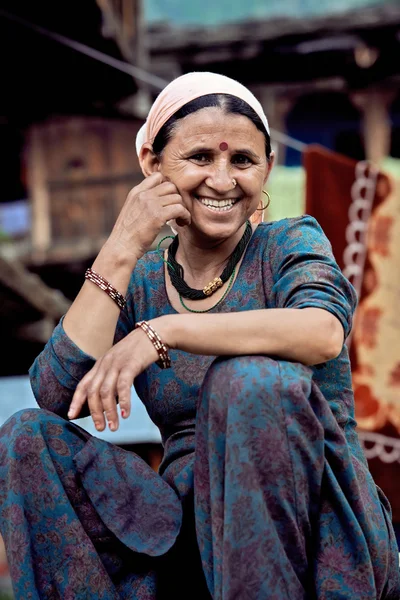 Rural Indian woman sitting in the courtyard of his house. Smiling at the camera.