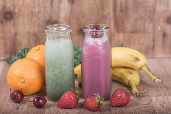 Två smoothie skakar i mjölkflaskor med färsk frukt — Stockfoto