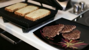 Kadın el elektrikli ızgara hafif bir ekmek alır ve biftek Closeup için bir tabak üzerinde bırakır .