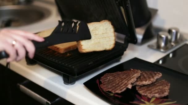 Kvinnlig hand förvandlar ett ljust bröd på en elektrisk grill. Närbild . — Stockvideo