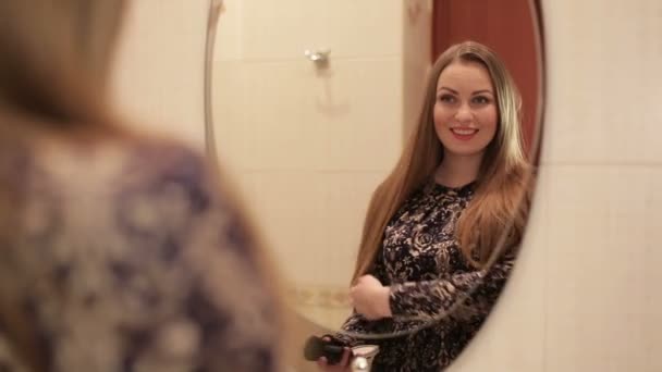 Beautiful woman doing make-up looking at the mirror in the interior of the bathroom in front of large window — Stock Video