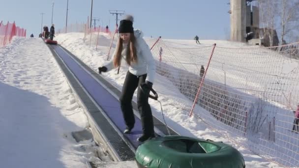 Belle fille va sur un ascenseur avec un traîneau gonflable à l'extérieur en hiver — Video