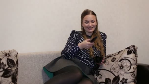 Vacker ung kvinna tittar på Tv, liggande på soffan bekvämt, ler och skrattar — Stockvideo