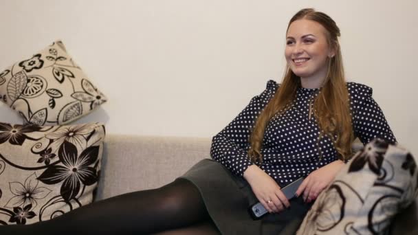 Hermosa mujer joven viendo la televisión, acostada en el sofá en la sala de estar en casa — Vídeos de Stock