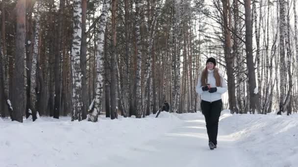 Feliz mujer sonriente con taza de café caliente o té al aire libre en invierno en el bosque — Vídeos de Stock
