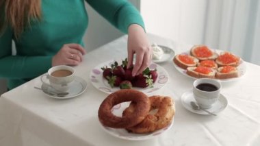 Yoğurt ve o yiyor daldırma el alır bir taze sulu çilek. Oturma odasında kahvaltı.