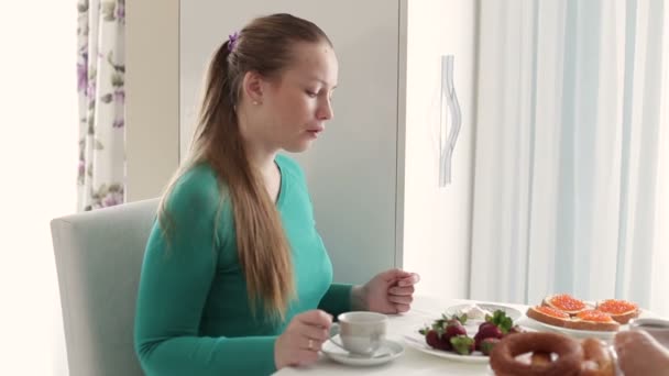 Ung kvinna med en kopp kaffe. Frukost på flickan. Kvinnor som dricker kaffe vid frukosten. — Stockvideo