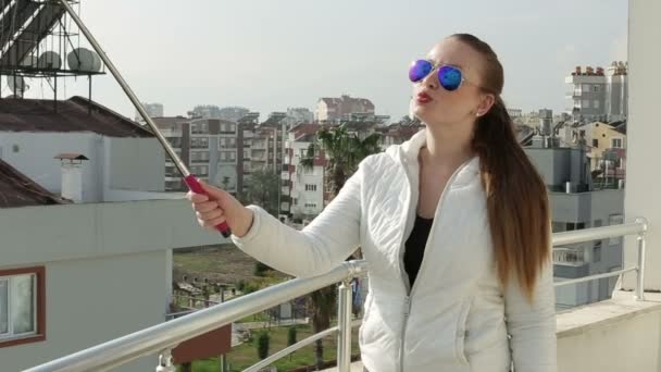 Молодая счастливая женщина делает автопортрет, стоя на крыше дома, используя камеру мобильного телефона смартфона. Крупный план. HD 1920x1080 . — стоковое видео