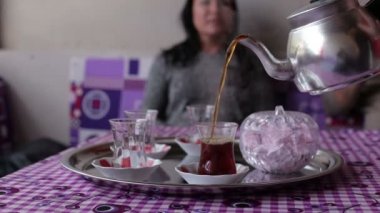 Yakın çekim, bir el dökülen çay çaydanlık siyah çay kase mans