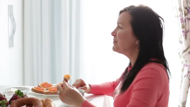 Жінка сидить біля вікна на сніданок. Крупним планом . — стокове відео
