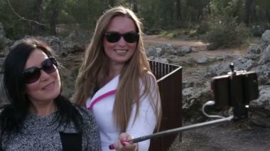 İki genç güzel kadın kendilerini park Caddesi üzerinde akıllı telefon kullanarak fotoğraf çekme