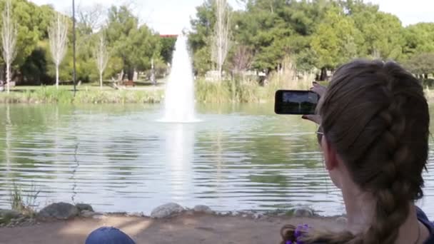 Güzel mutlu genç kız güneş ışıklarıyla Smartphone kullanarak fotoğraf yapma — Stok video