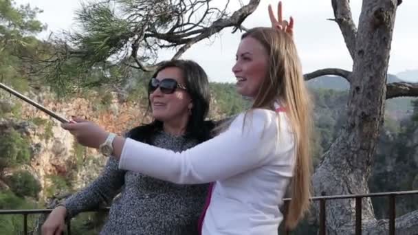 Twee jonge mooie vrouwen fotograferen zelf met behulp van slimme telefoon in het park — Stockvideo