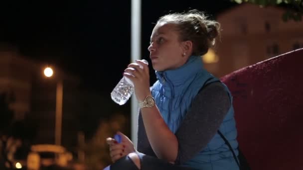 Η όμορφη κοπέλα να μιλάει και να πίνει νερό από ένα μπουκάλι. — Αρχείο Βίντεο