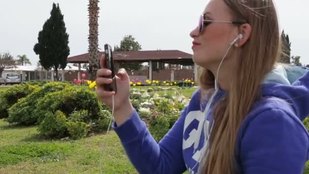 Mulher bonita ouvindo música em fones de ouvido usar um smartphone — Vídeo de Stock