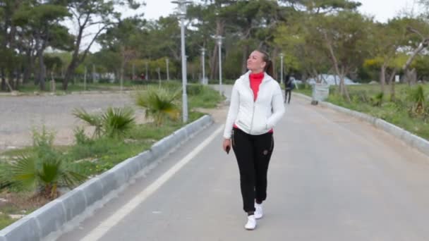 Fille heureuse réfléchie souriant marchant dehors dans le parc — Video