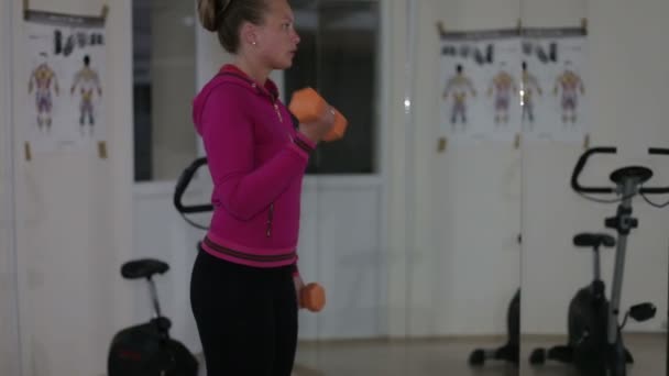 Junge schöne Mädchen geht in für den Sport verwenden einer Hantel in der Turnhalle — Stockvideo