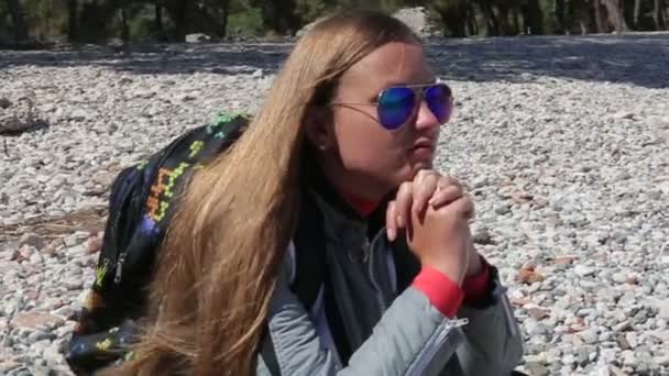 Menina bonita agachamentos na praia na praia de seixos — Vídeo de Stock