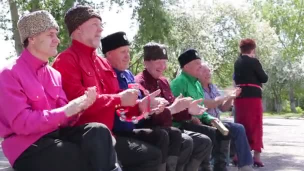 Kurgan, Oroszország - lehet 2016: idős ember ül a padokon játszani zenei eszközök, és énekelni kívül nyáron — Stock videók