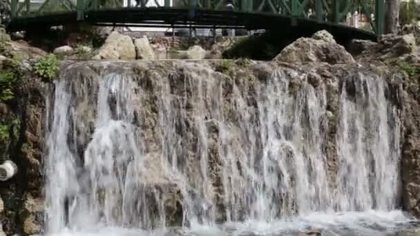 Красивая женщина флиртует улыбаясь и стоя возле водопада — стоковое видео