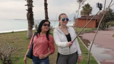 Kendi kendine portre smartphone cep telefonu kamera kullanarak sahilinde alarak iki genç kadın.