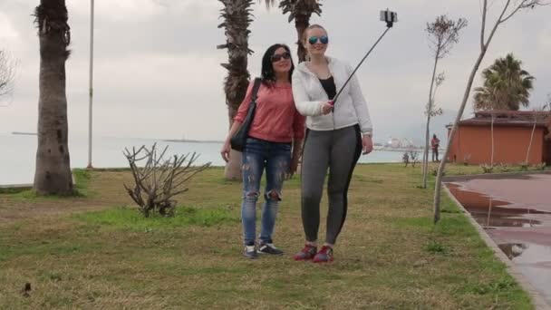 Dos mujer joven tomando autorretrato en el paseo marítimo usando la cámara del teléfono celular del teléfono inteligente . — Vídeo de stock