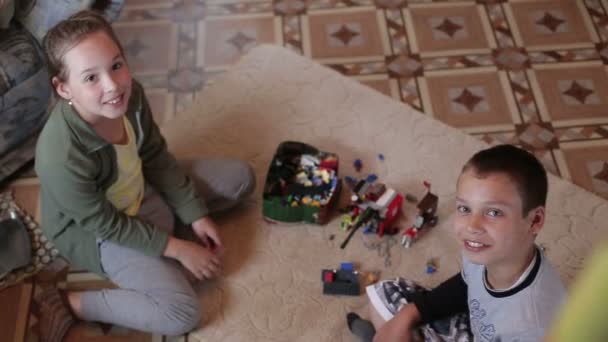 Chico y chica están jugando en casa sentado en la alfombra — Vídeos de Stock