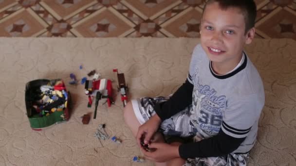 Un niño jugando en casa sentado en la alfombra — Vídeo de stock