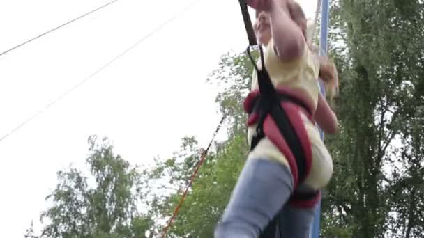 En flicka hoppar på studsmattan i parken sommaren — Stockvideo