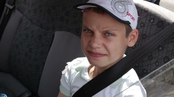 Menino sentado no banco de trás de um carro usando cinto de segurança — Vídeo de Stock
