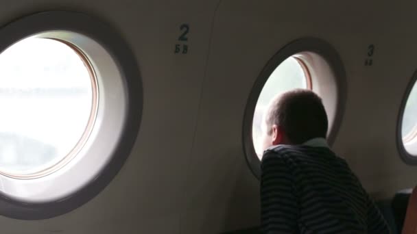 Chico mirando una ventana de avión — Vídeos de Stock