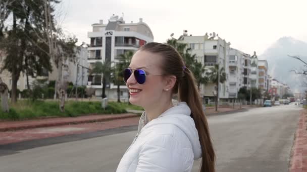 Красивая девушка в солнечных очках стоит на улице — стоковое видео