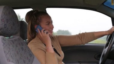 Genç güzel kız konuşmak bir arabanın direksiyonuna otururken smartphone kullanın