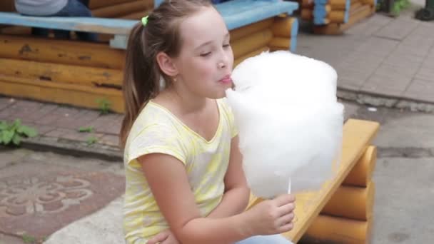 Cheerful little girl is eating cotton candy, close-up — Stock Video