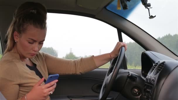 Young girl sitting behind the wheel car use smartphone — Stock Video