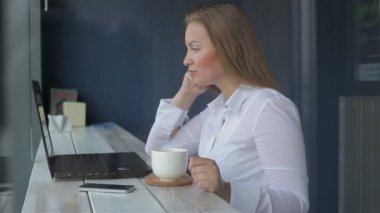 Bir dizüstü bilgisayar kullanarak bir masada oturan güzel iş kadını