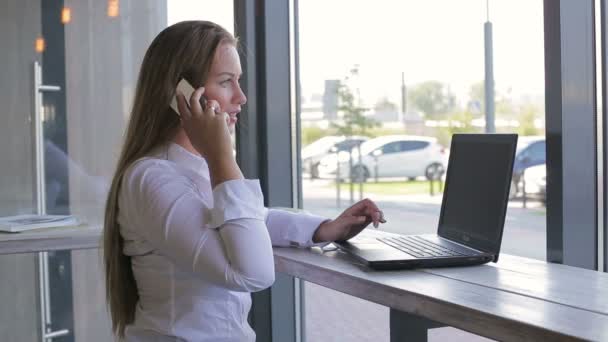 Donna d'affari che parla con uno smartphone, utilizzare il computer portatile — Video Stock