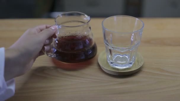 Vrouwelijke hand giet de thee in een glas — Stockvideo