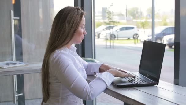Vacker affärskvinna sitter vid ett skrivbord med en bärbar dator — Stockvideo