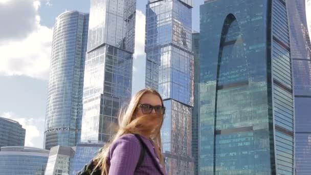 Beautiful woman tourist standing on the background of a large skyscraper — Stock Video