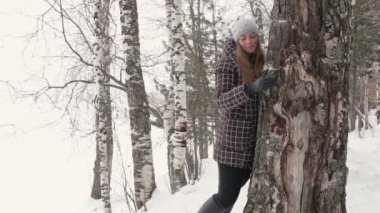 Kış ormanda yürüyüş ve bir ağaç sarılma genç bir kadın
